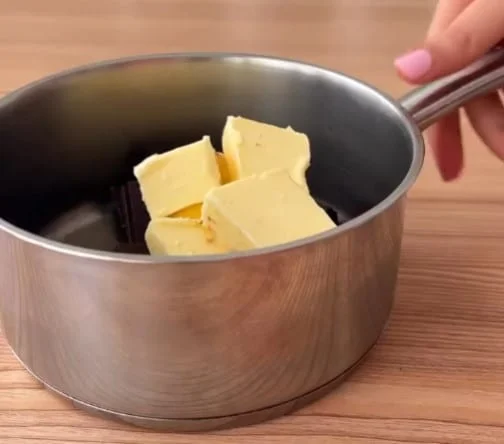 Chunks of butter and dark chocolate in a silver pot, ready to be melted
