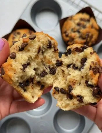 A freshly baked mini chocolate chip muffin split in half, revealing a fluffy inside dotted with chocolate chips