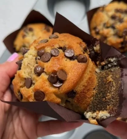 Holding a mini chocolate chip muffin with the paper liner peeled back, ready to enjoy