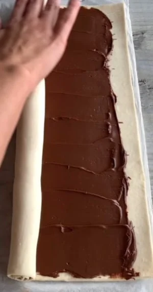 rolling puff pastry, preparing for a sweet, nutella filled pastry roll